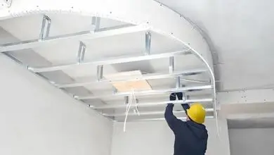 Stavebník montuje kovový rám pro zakřivený sádrokartonový strop.