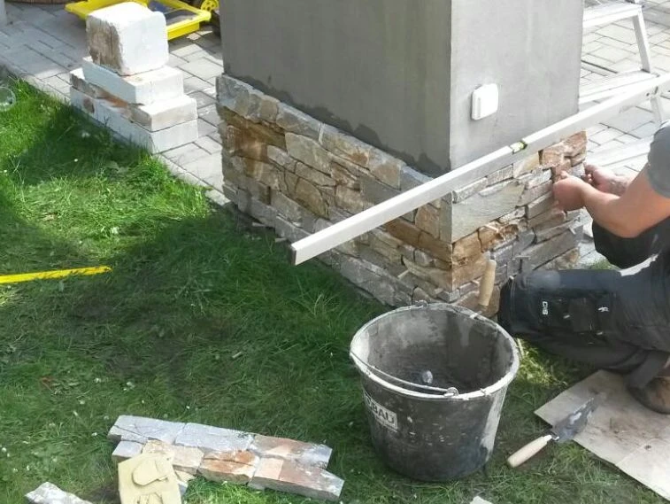 Montáž obkladu z umělého kamene na fasádu s použitím lepidla.