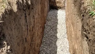 Zásyp štěrkem v vykopaném příkopu pro drenáž kolem domu.