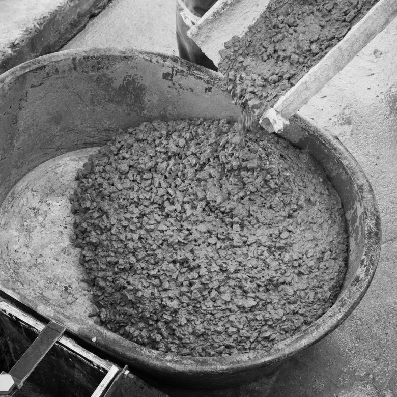 Svěží beton s kamenivem se nalévá do kbelíku.