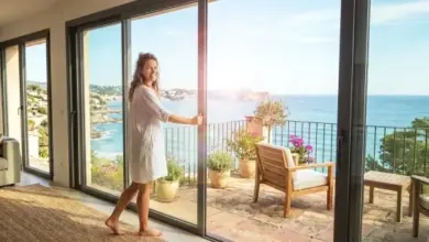 Žena otevírá skluzavky vedoucí na balkon s výhledem do moře.