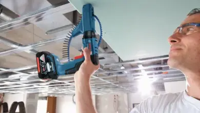 Muž montuje kazetový strop pomocí elektrického šroubováku.