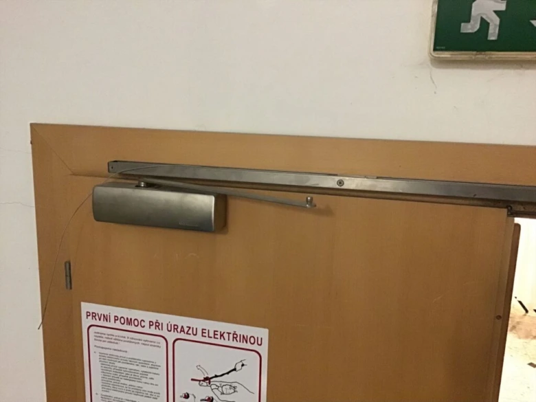 Dveře na únikové cestě s varovným štítkem a pokyny pro první pomoc.