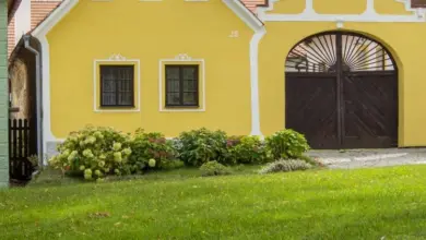 Žlutý dům s rokem výstavby na fasádě ukazuje jak zjistit stáří domu.