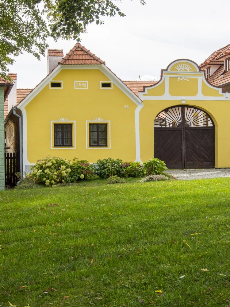 Žlutý dům s rokem výstavby na fasádě ukazuje jak zjistit stáří domu.