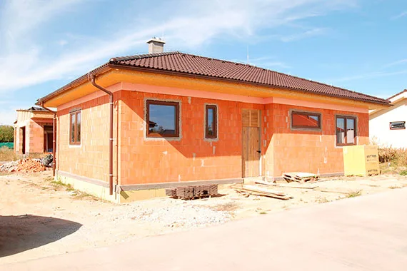 Dům z porobetonu v oranžové barvě s okny na fasádě.