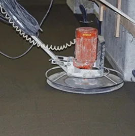 Elektrická bruska pro úpravu povrchu betonu ve stavbě.
