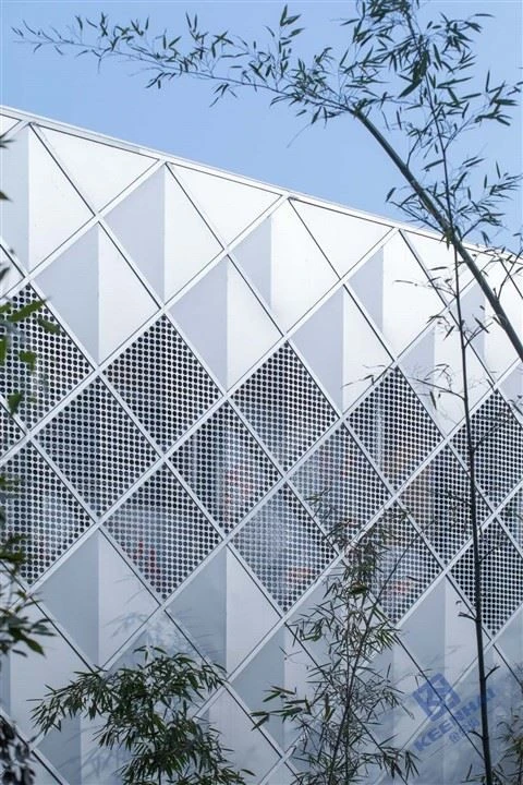 Modernní fasáda s geometrickým vzorem z bílých panelů.