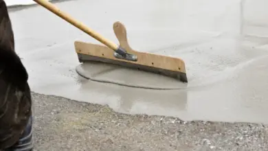 Pracovník vyrovnává čerstvý beton v garáži pomocí pravítka.