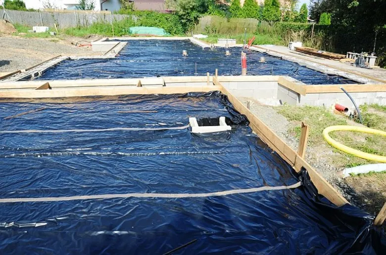 Černá hydroizolační fólie pod betonovou deskou na staveništi.
