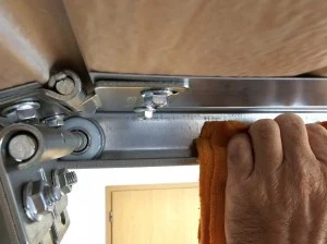 Ruční údržba mechanismu sekčního garážového brána s kolejnicí.