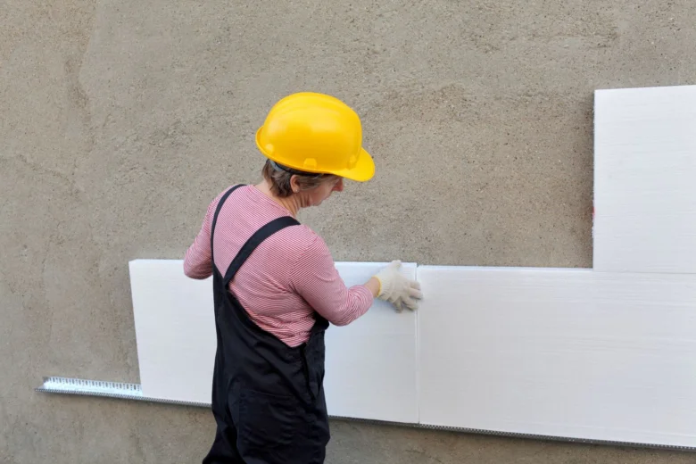Stavebník montuje alternativní izolační desky na betonovou stěnu.