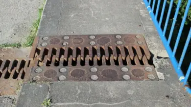 Rusty kovová mřížka v betonu ukazuje praskliny.