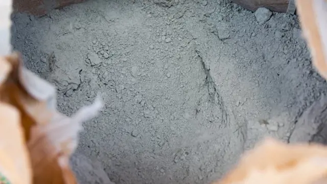 Sáček s šedým cementovým práškem pro stavební použití.