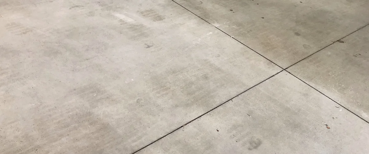 Betonová podlaha s viditelnými dilatačními spárami tvořícími křížový vzor.