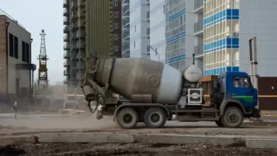 Modrý betonový smíchávač na staveništi s vysokými budovami.