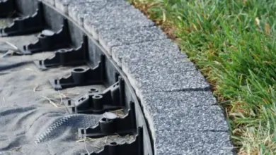 Křivá betonová opěrná zeď s výztužnou fólií na trávníku.