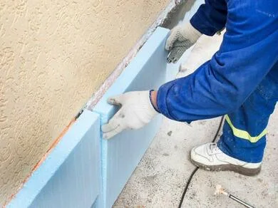 Montáž desky z extrudovaného polystyrénu na stěnu.