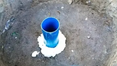 Modrá plastová trubice v jámě pro studnu s bílým těsněním.