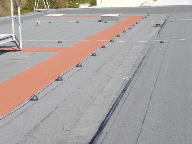 Střešní lepenka s oranžovým pásem na ploché střeše.