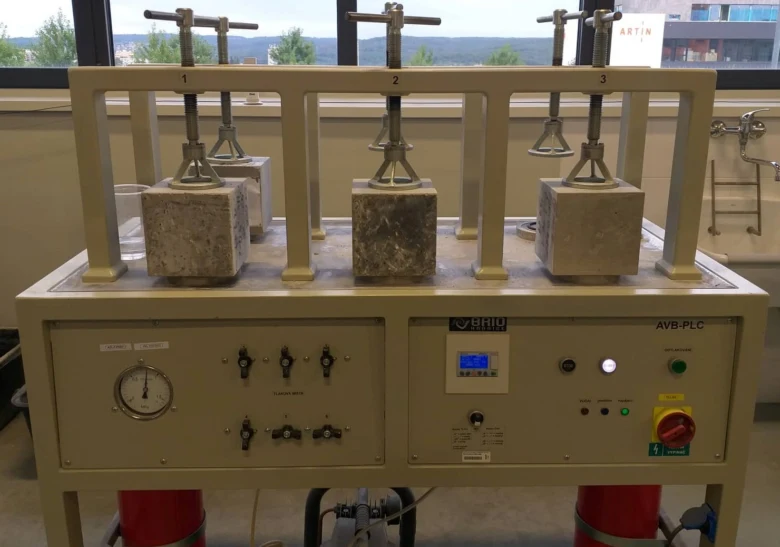 Laboratorní zařízení pro testování pevnosti betonových kostek po tvrdnutí.
