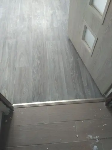 Dřevěná vnitřní dveře s prahem na podlaze ukazuje mezeru.