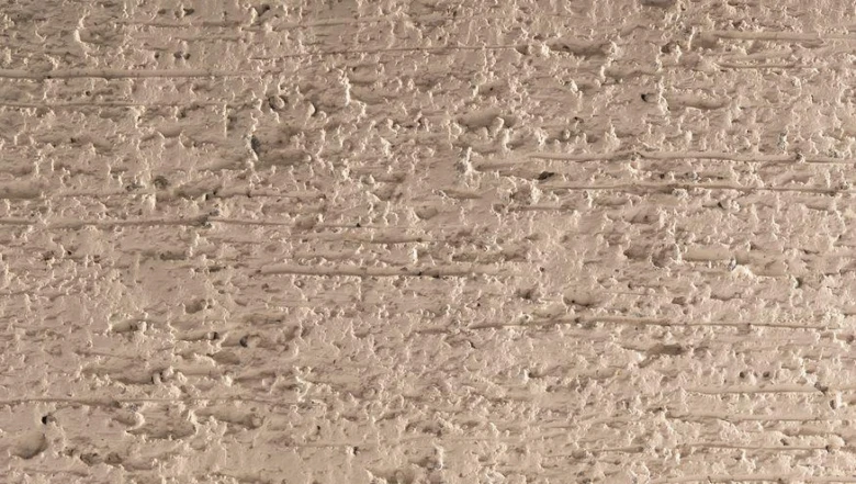 Texturovaný povrch polymerového písku s jemnými vodorovnými pruhy.