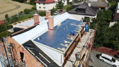 Montáž modrých PIR desek na střešní izolaci s dřevěnými nosiči.