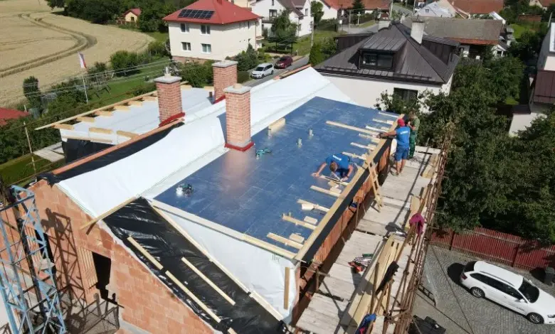 Montáž modrých PIR desek na střešní izolaci s dřevěnými nosiči.