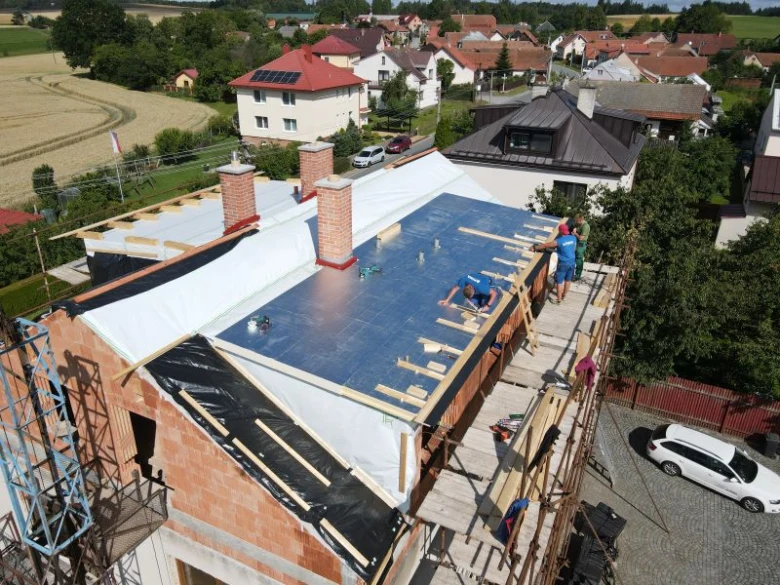 Montáž modrých PIR desek na střešní izolaci s dřevěnými nosiči.