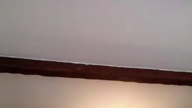 Falešné dřevěné trámy na bílém stropu s lustry.