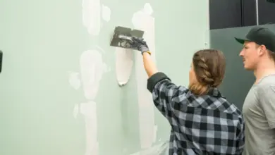 Člověk nanáší špachtlíkem stěnovou hmotu na vnitřní zeď.