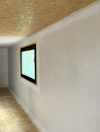 Zateplená vnitřní stěna s oknem ve chodbě po úpravách.
