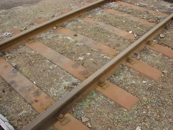 Rusty železniční pražce s kolejnicemi na štěrku.