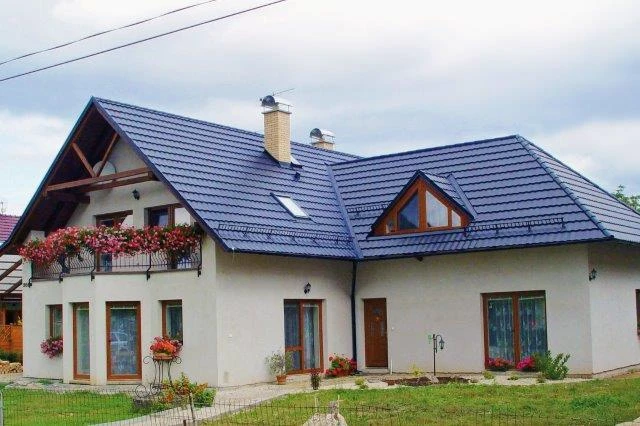 Dokončená montáž modré plechové střešní krytiny na rodinném domě.