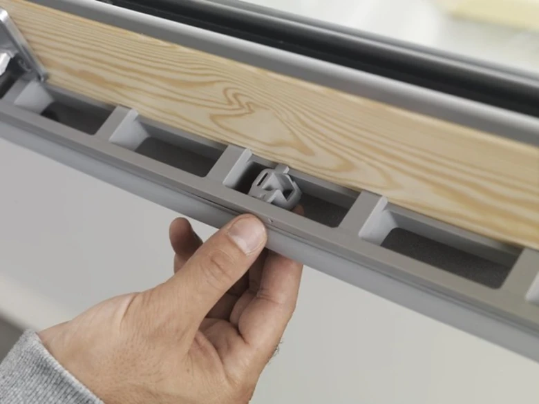Detailní pohled na údržbu střešního okna s odhaleným vnitřním mechanismem.