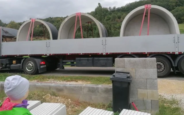 Doprava velkých betonových kanalizačních trubek na kamionu venku.