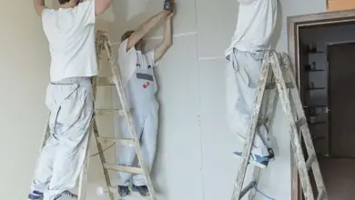 Tři muži montují stropní panely na kovové lišty.
