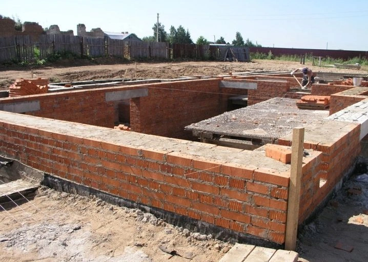 Stavba nosné cihlové stěny nového domu na pozemku.