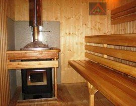 Sauna s kamny a komínovou trubkou v dřevěném interiéru