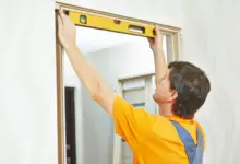 Muž měří vnitřní dveře úrovní při instalaci rámu.