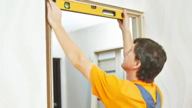 Muž měří vnitřní dveře úrovní při instalaci rámu.