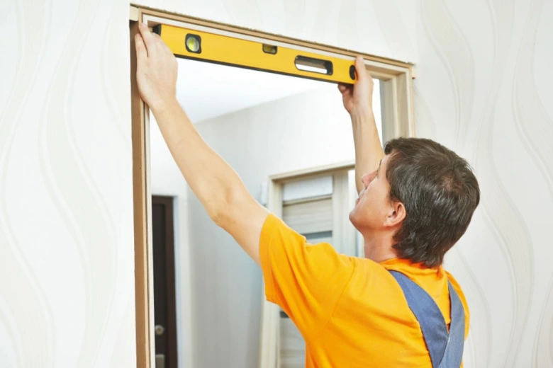 Muž měří vnitřní dveře úrovní při instalaci rámu.