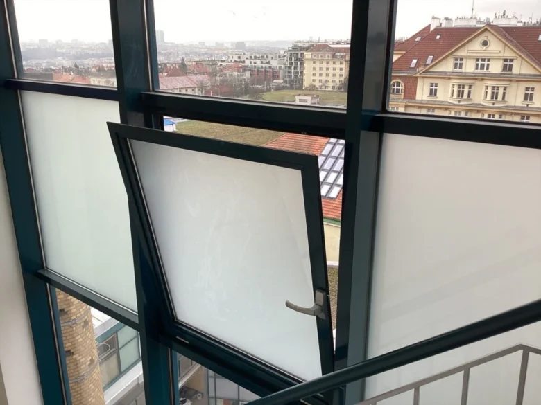Otevřené okno na únikové cestě s výhledem do města.