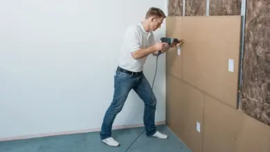 Muž montuje příčku z kartonových panelů na kovové nosníky.