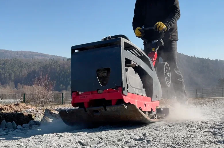 Pracovník s vibračním válcem na přípravné vrstvě pro dlažbu.