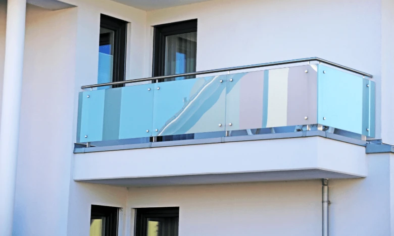 Moderní skleněné zábradlí na balkóně s nerezovými rukojetmi.