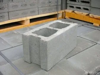 Jedna betonová cihla leží na podlaze vedle palet s dalšími.