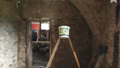 Interiér domu v opravě s viditelnými cihlovými zdmi a nářadím.