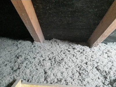 Bílá volná izolace mezi dřevěnými trámy v podkroví.